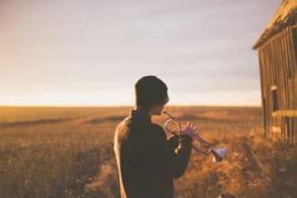 Ученые назвали лучшую музыку для сна/Фото: Priscilla Du Preez/Unsplash Мужчина с трубой в поле