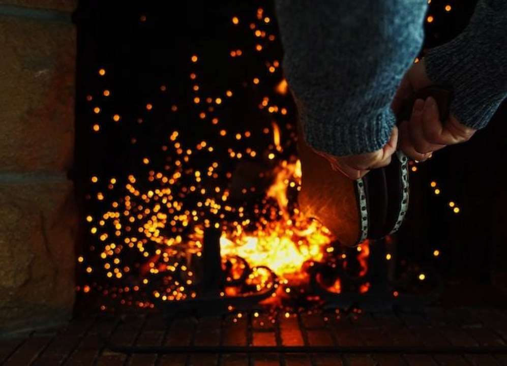 Чоловік роздмухує багаття міхом