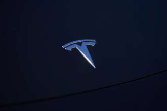 Tesla отзывает более миллиона автомобилей из-за проблем с окнами/Фото: Allison Dinner/Getty Images Логотип Tesla на капоте черного автомобиля