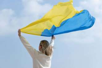 Україна стала країною року / Фото: Freepik Жінка тримає прапор України