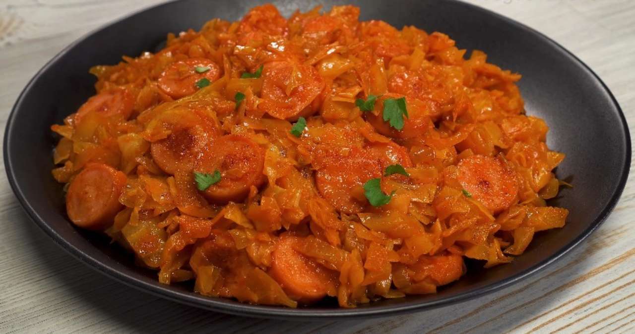 Тушеная капуста с колбасками на тарелке
