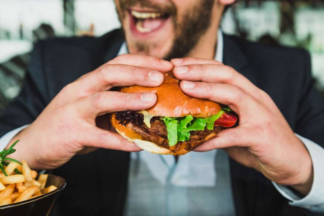 Найпопулярніша їжа у світі: топ-50 продуктів з усієї планети/Фото: Sander Dalhuisen/Unsplash Чоловік їсть гамбургер