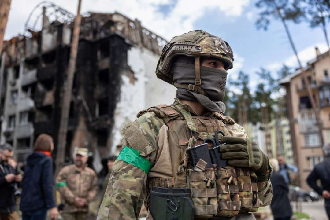 Ветераны будут преподавать военную подготовку в украинских школах/Фото: John Moore/Getty Images Украинский военный на фоне разрушенного дома
