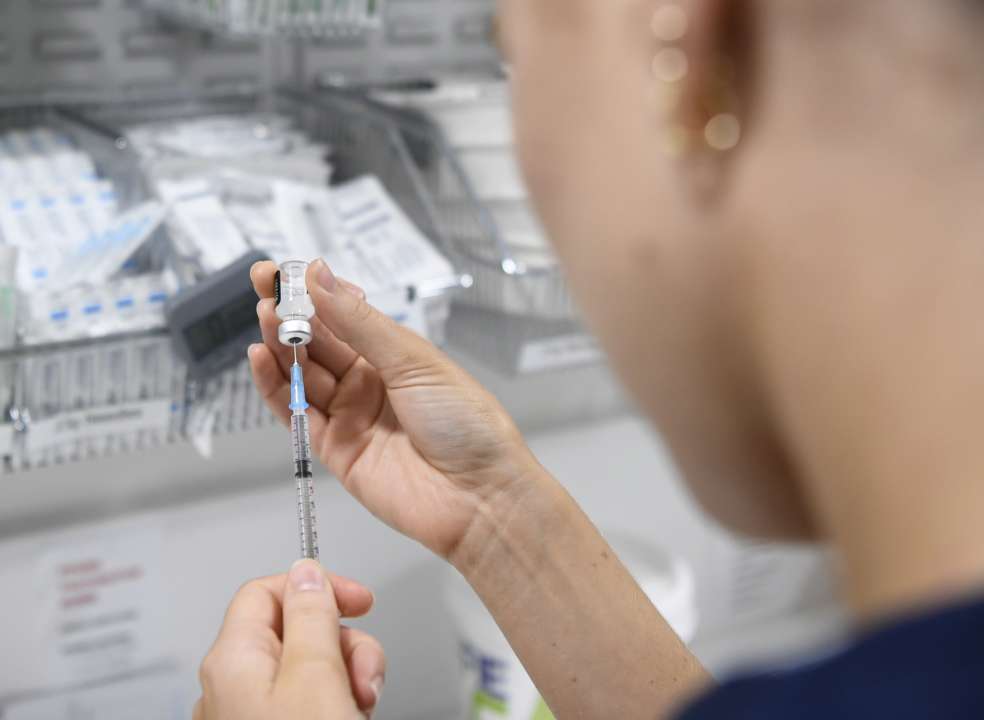 Лікар набирає вакцину від коронавірусу в шприц
